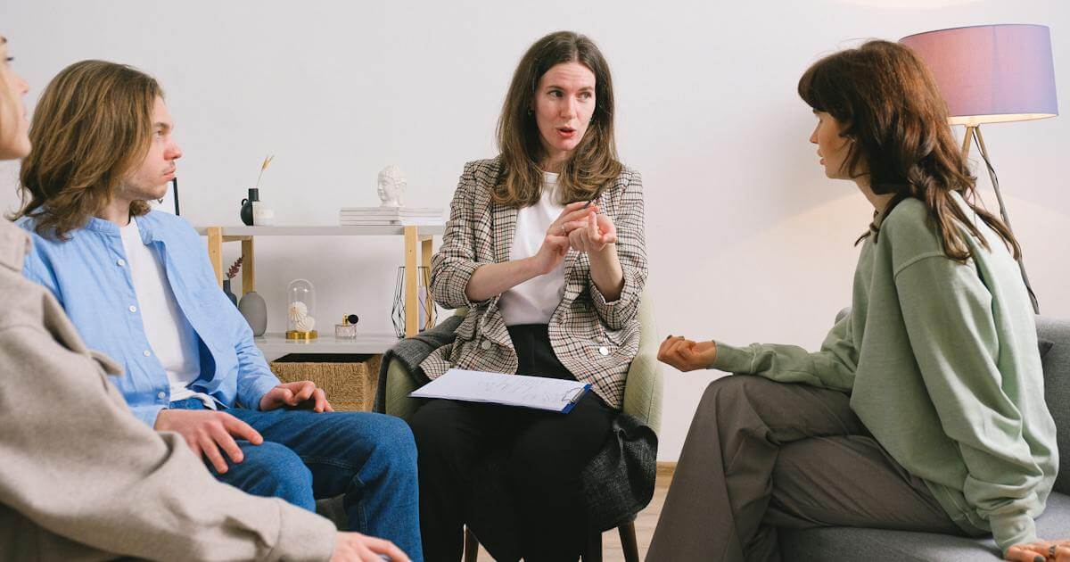 A woman engaging in therapy with three other women in a room.
